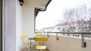 Un balcón con una mesa y sillas, vistas a edificios y una barandilla.