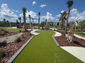 A landscaped area with a winding path, palm trees, and a giraffe statue. - Disney Getaway! Private Pool & Game Room. Book Now! #WC81 (Orlando)