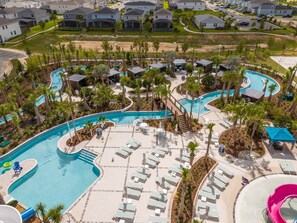 A resort with a large pool area, multiple lounge chairs, and a small water slide. - Disney Getaway! Private Pool & Game Room. Book Now! #WC81 (Orlando)