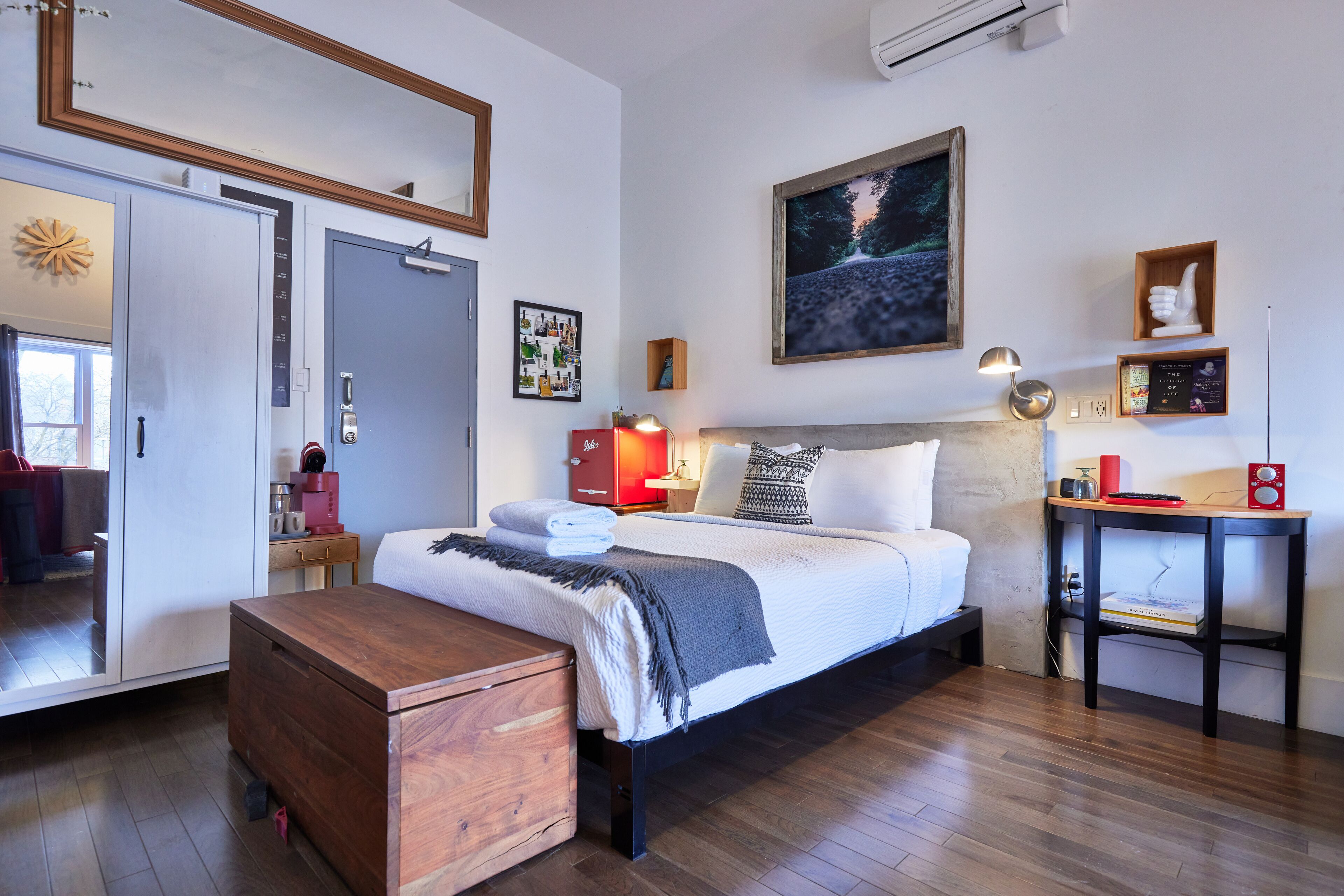 A bedroom with a bed, bedside table, and a wooden chest of drawers.