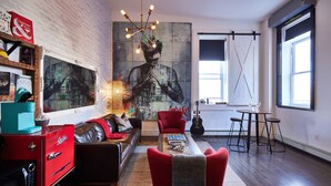 A modern living room with a red sofa, a coffee table, and a large abstract painting on the wall. - Edisons Inn (Stratford)