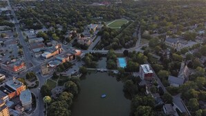 An aerial view of a town with a central lake, surrounded by residential and commercial buildings, including a prominent church with a steeple. - Edisons Inn (Stratford)