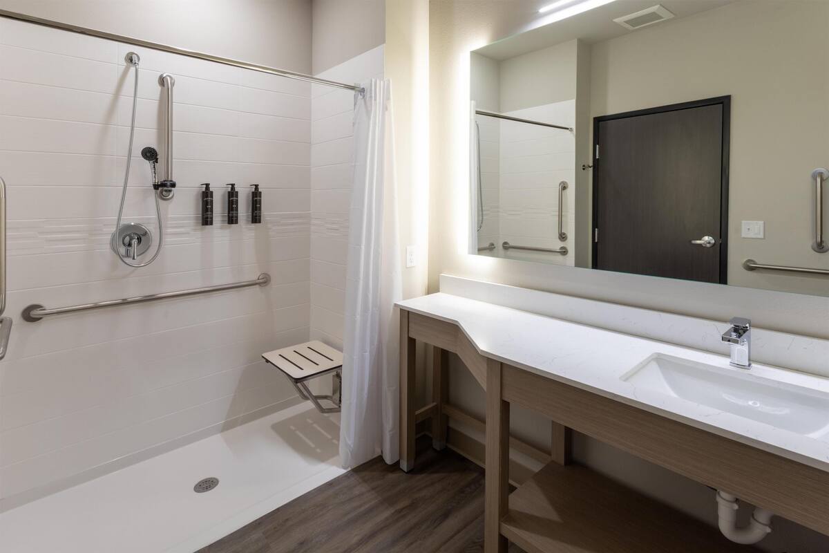 Un bagno moderno con doccia, lavandino e specchio.