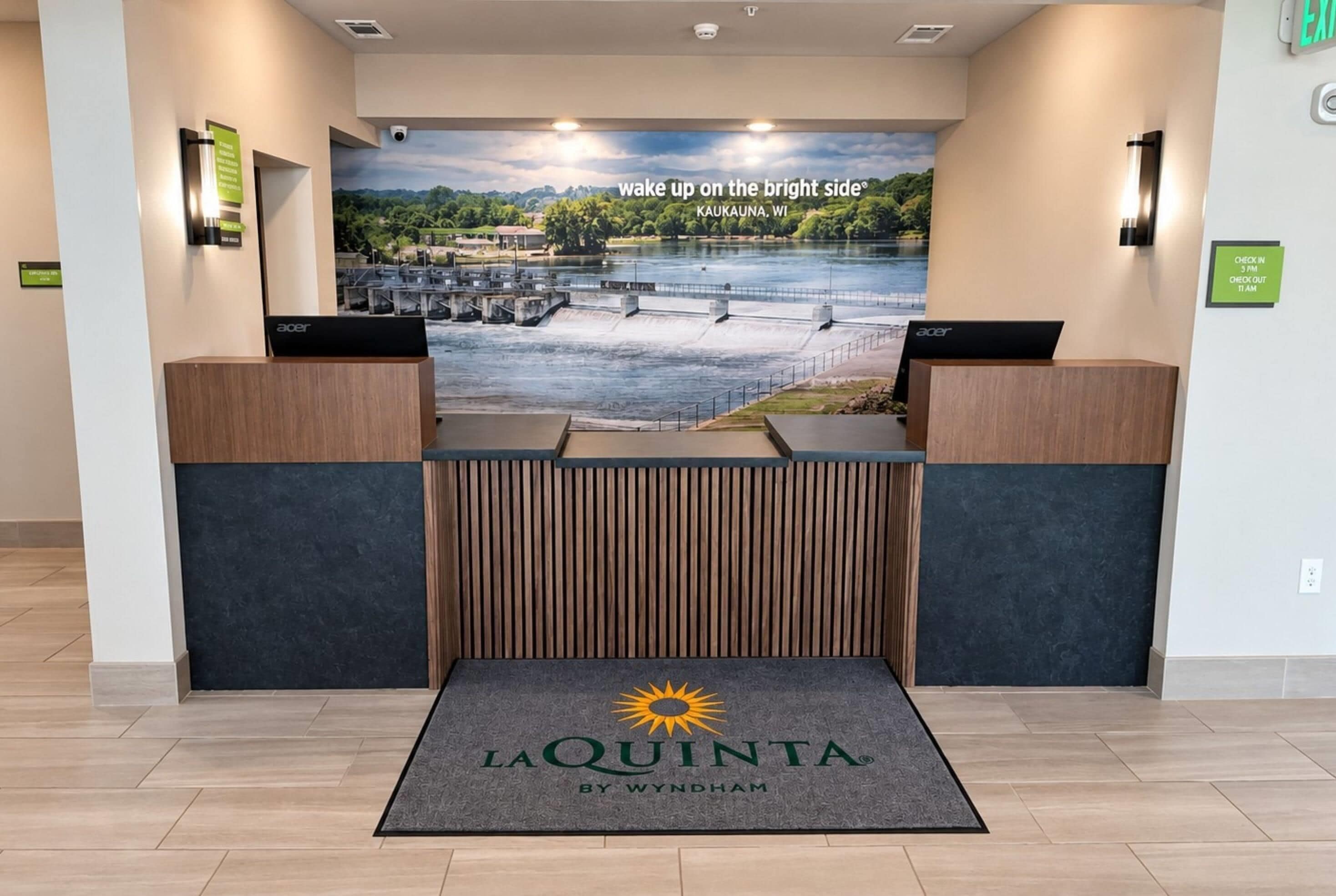 A reception desk with a view of a river and a sign that reads 'wake up on the bright side Kaukauna, WI'.