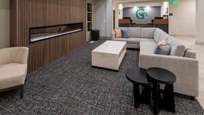 Een moderne lobby met een open haard, banken, een salontafel en een receptiebalie.