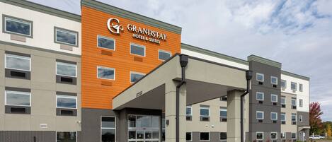 A modern hotel with a prominent sign, a covered entrance, and a parking lot.