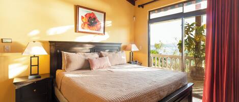 A bedroom with a bed, two bedside tables, a nightstand, a window with a view, and a ceiling fan.