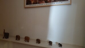Un mur orné d’un tableau encadré représentant des lions et une étagère sur laquelle sont posées des statuettes d’éléphants.