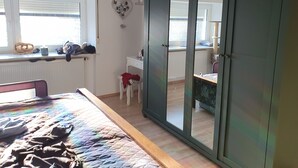 Une chambre à coucher avec un lit, une commode, un miroir et une fenêtre.