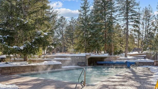 A swimming pool surrounded by snow-covered trees and a brick pathway. - The Powder Haven Chalet (Park City)