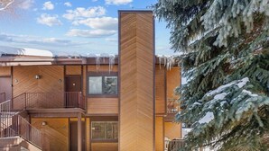 A two-story building with a central chimney, a covered entrance, and a staircase leading to the upper floor. - The Powder Haven Chalet (Park City)