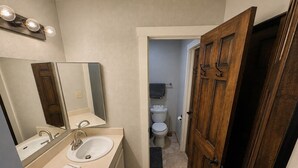 A bathroom with a sink, mirror, and wooden door. - The Powder Haven Chalet (Park City)