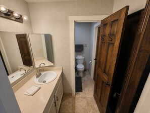 A bathroom with a sink, mirror, and wooden door. - The Powder Haven Chalet (Park City)