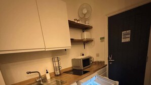 Une cuisine compacte équipée d’un évier, d’un four à micro-ondes et d’un réfrigérateur ouvert.