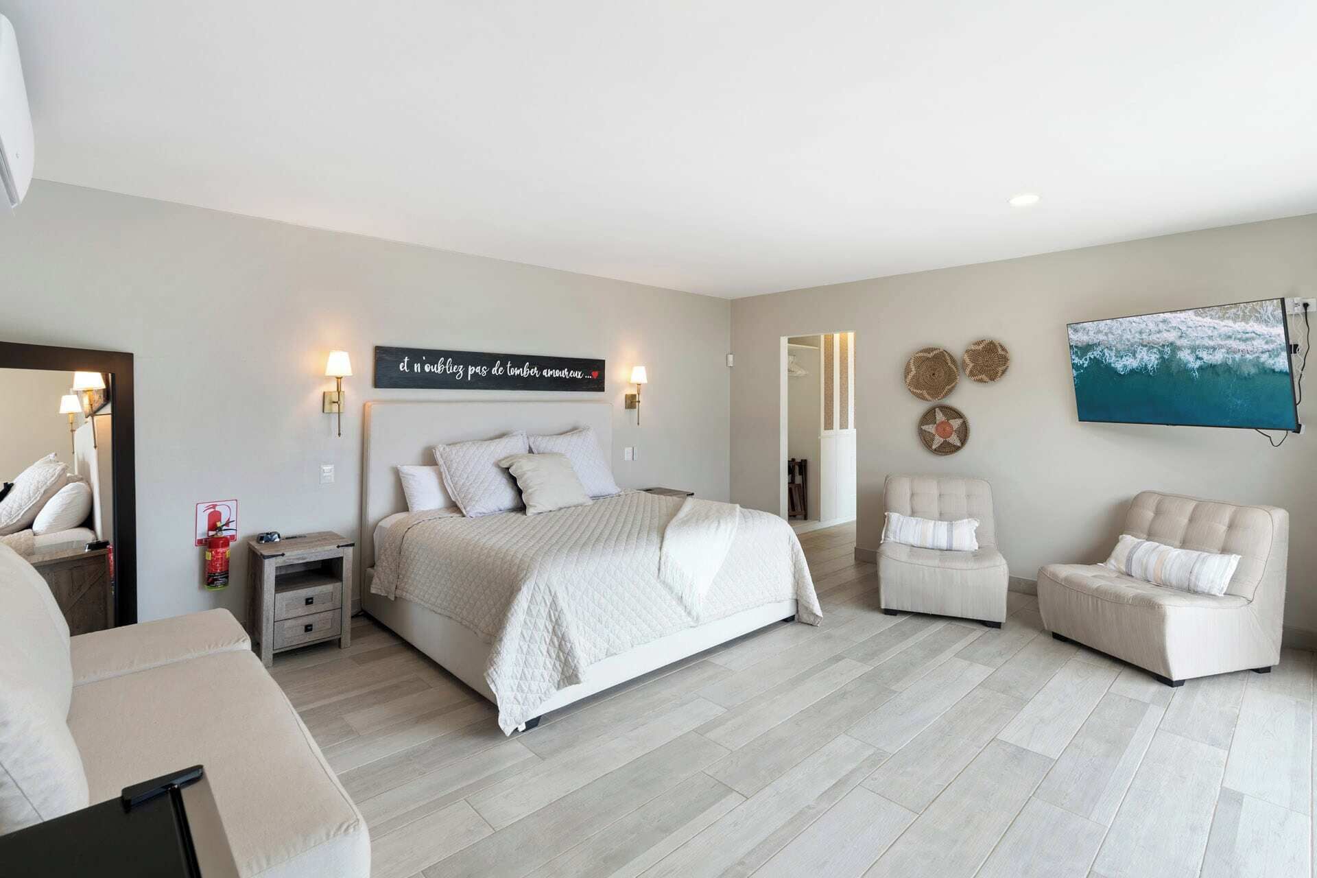 Une chambre moderne avec un grand lit, deux tables de chevet, un téléviseur à écran plat et une œuvre d’art accrochée au mur.