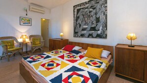A hotel room with a large bed, two chairs, a nightstand with a lamp, a wooden cabinet, and a painting on the wall. - Enchanting apartment with WiFi in beautiful Brela with a loggia (Brela)