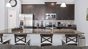 A kitchen with dark cabinets, stainless steel appliances, a granite countertop, and pendant lighting. - Disney Getaway! Townhouse with Private Pool. Book Now! #SLR476 (Orlando)