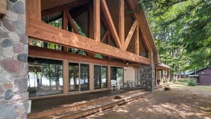 Une cabane avec une façade en pierre, de grandes fenêtres et une terrasse en bois.