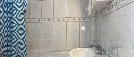 A bathroom with a bathtub, a sink, and a shower curtain.