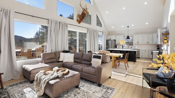 A spacious living area with a large sofa, a dining table, and a kitchen in the background. - 3BR Divide Cabin: Starlink, Mtn Views, Hiking Access! Family Friendly - Sleeps 8 (Divide)
