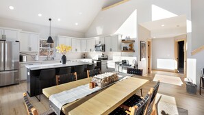 A modern kitchen with a central island, white cabinetry, and a dining area with a long table. - 3BR Divide Cabin: Starlink, Mtn Views, Hiking Access! Family Friendly - Sleeps 8 (Divide)