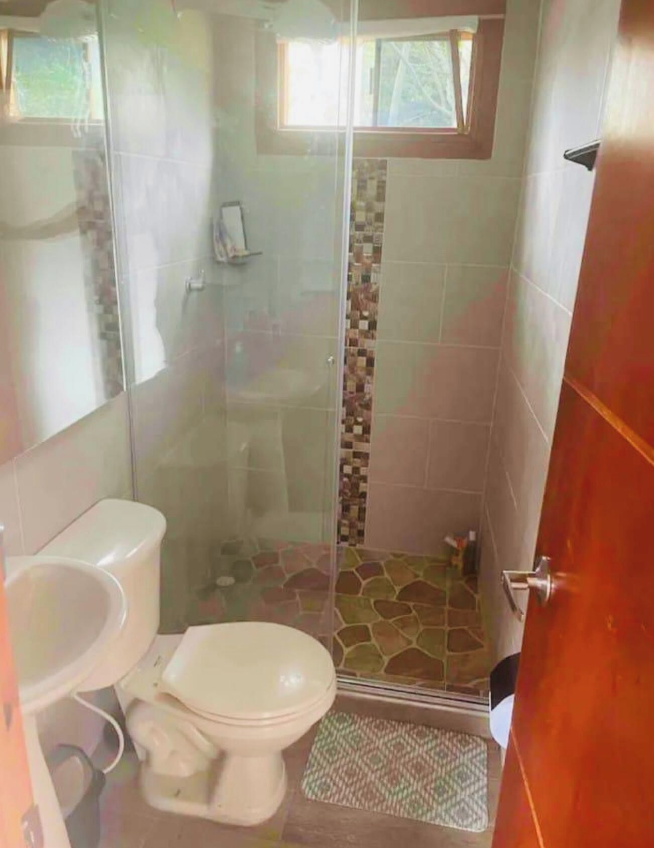 A bathroom with a glass-enclosed shower, a toilet, and a sink.