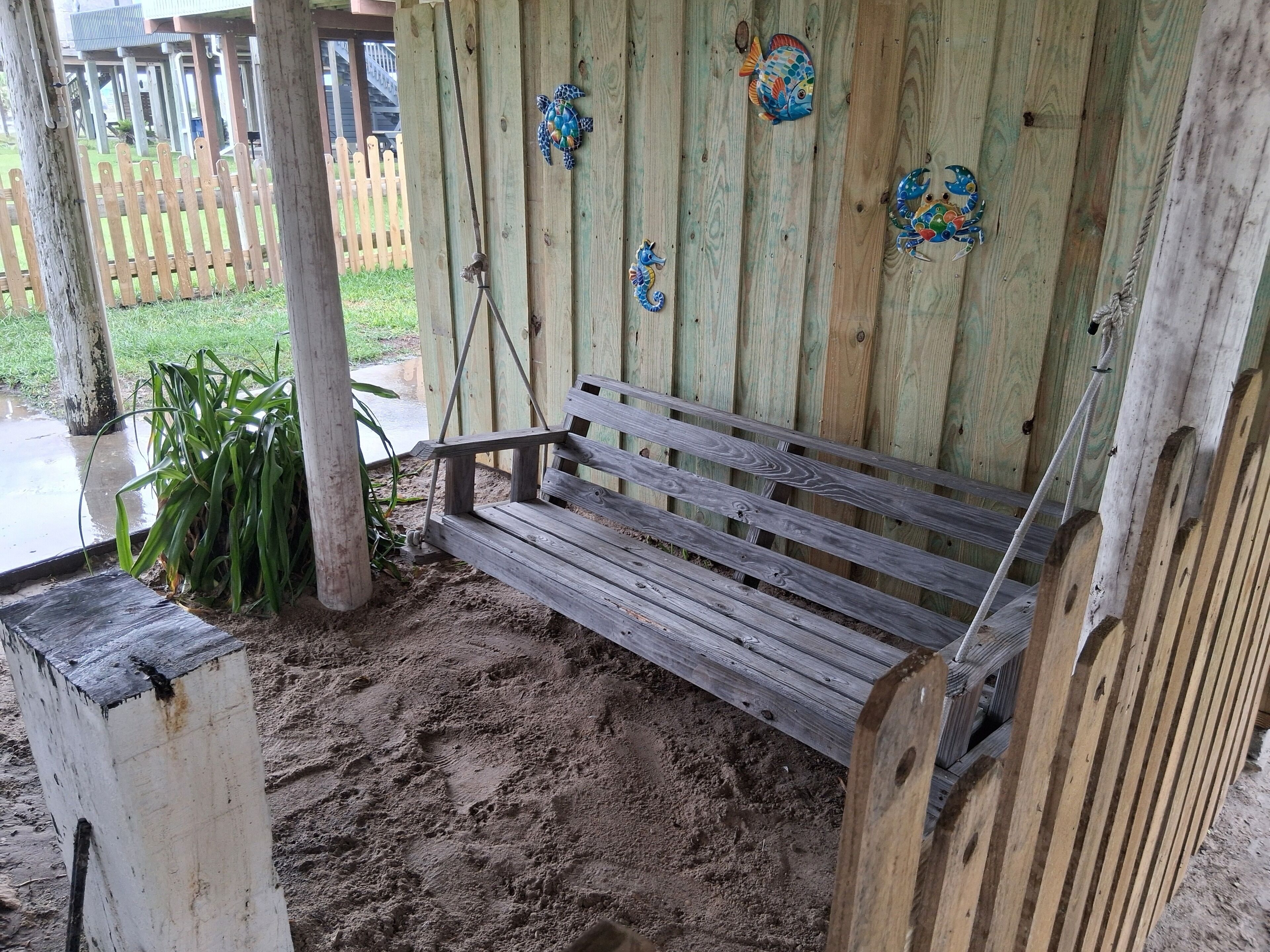 Un banco de madera bajo una estructura de madera con adornos de peces y cangrejos en la pared.