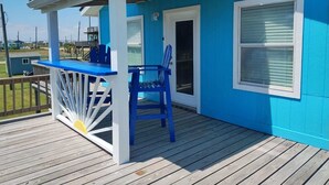 Ein blaues Haus mit Veranda, Tisch und zwei Stühlen.