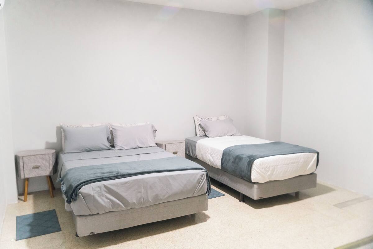A bedroom with two beds, a nightstand, and a small drawer unit.