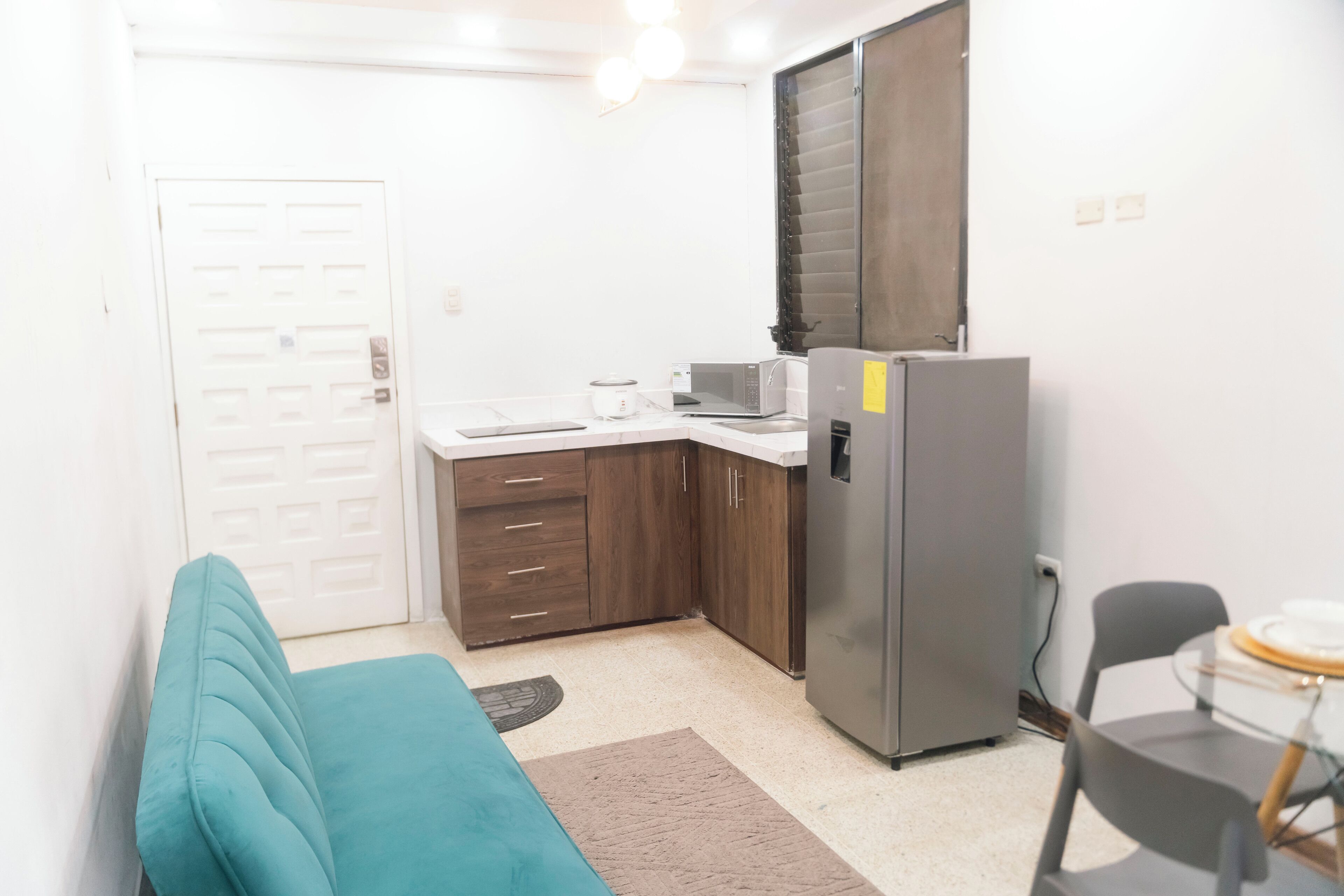A compact kitchen with a refrigerator, microwave, and a small dining area with a table and chairs.