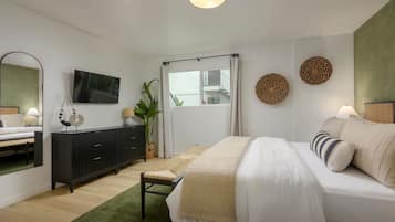 A modern bedroom with a bed, a TV, a dresser, and a large window.