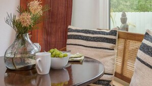 A cozy seating area with a round table, a vase with flowers, and a bowl of green grapes. - Private Garden | Family Friendly (Summerland)