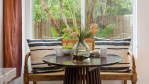 A room with a wooden bench, a round table, and a window with a view of greenery. - Private Garden | Family Friendly (Summerland)