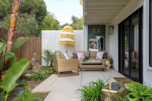 A patio area with wicker furniture, a Buddha statue, and a decorative umbrella.