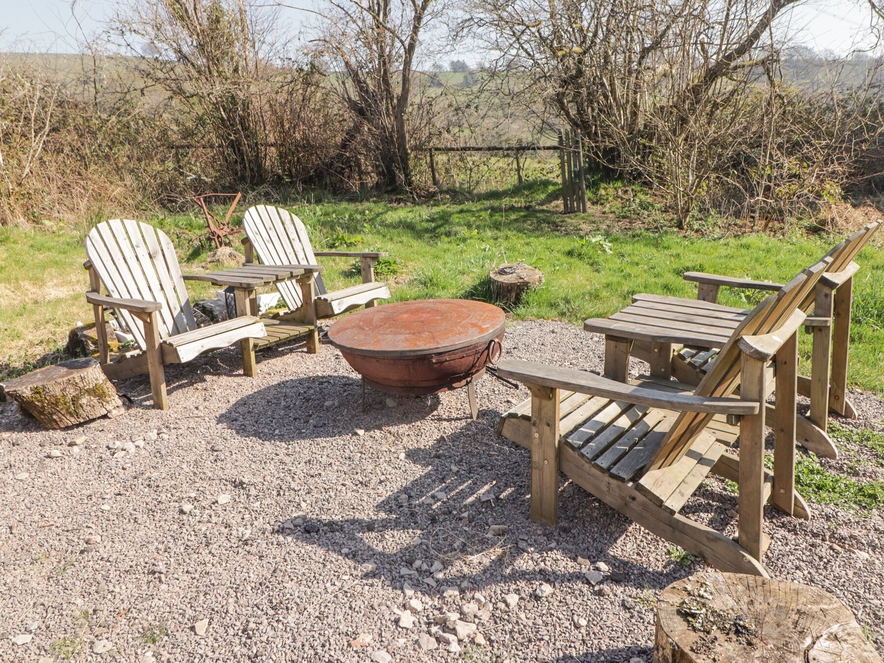 A rustic outdoor seating area with Adirondack chairs and a fire pit.