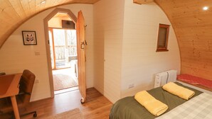 A cozy attic bedroom with a wooden ceiling, a bed with a green and white checkered bedspread, a wooden desk, and a chair. - Cabanau Bach (Caerphilly)