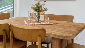 Ein Essbereich mit Holztisch, Stühlen, einer Pendelleuchte und einem gerahmten Gemälde an der Wand.