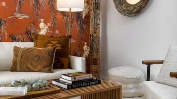 A living room with a sofa, a coffee table, a lamp, and a wall with a patterned wallpaper.