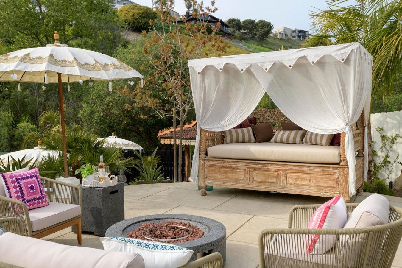 A patio with a canopy bed, outdoor furniture, and a fire pit.