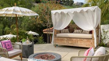 A patio with a canopy bed, outdoor furniture, and a fire pit.