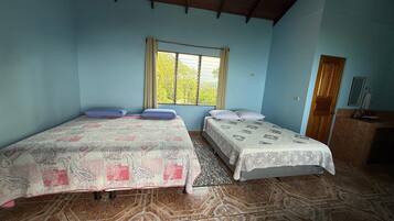A room with two beds, a window, a wooden ceiling, and a tiled floor.