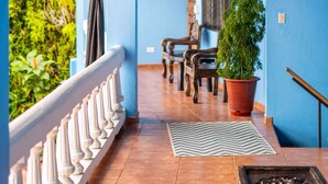 Une pièce aux murs bleus, ornée d’une balustrade blanche, d’un banc en bois, d’une plante en pot et d’un tapis à motifs.