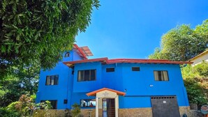 Un bâtiment à deux étages, avec une façade bleue, un toit rouge et une base en pierre.