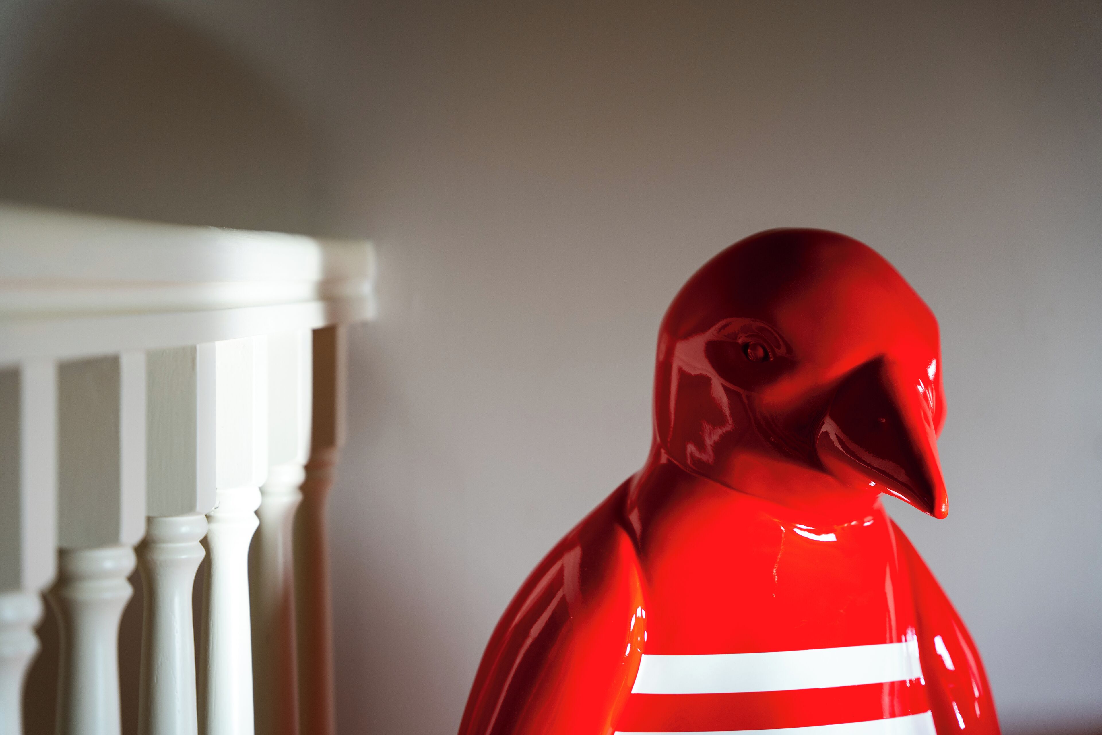 A red object with a white stripe, possibly a toy or decorative item, next to a white railing.