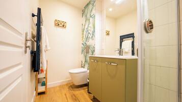 A compact bathroom with a toilet, a sink, and a shower area.