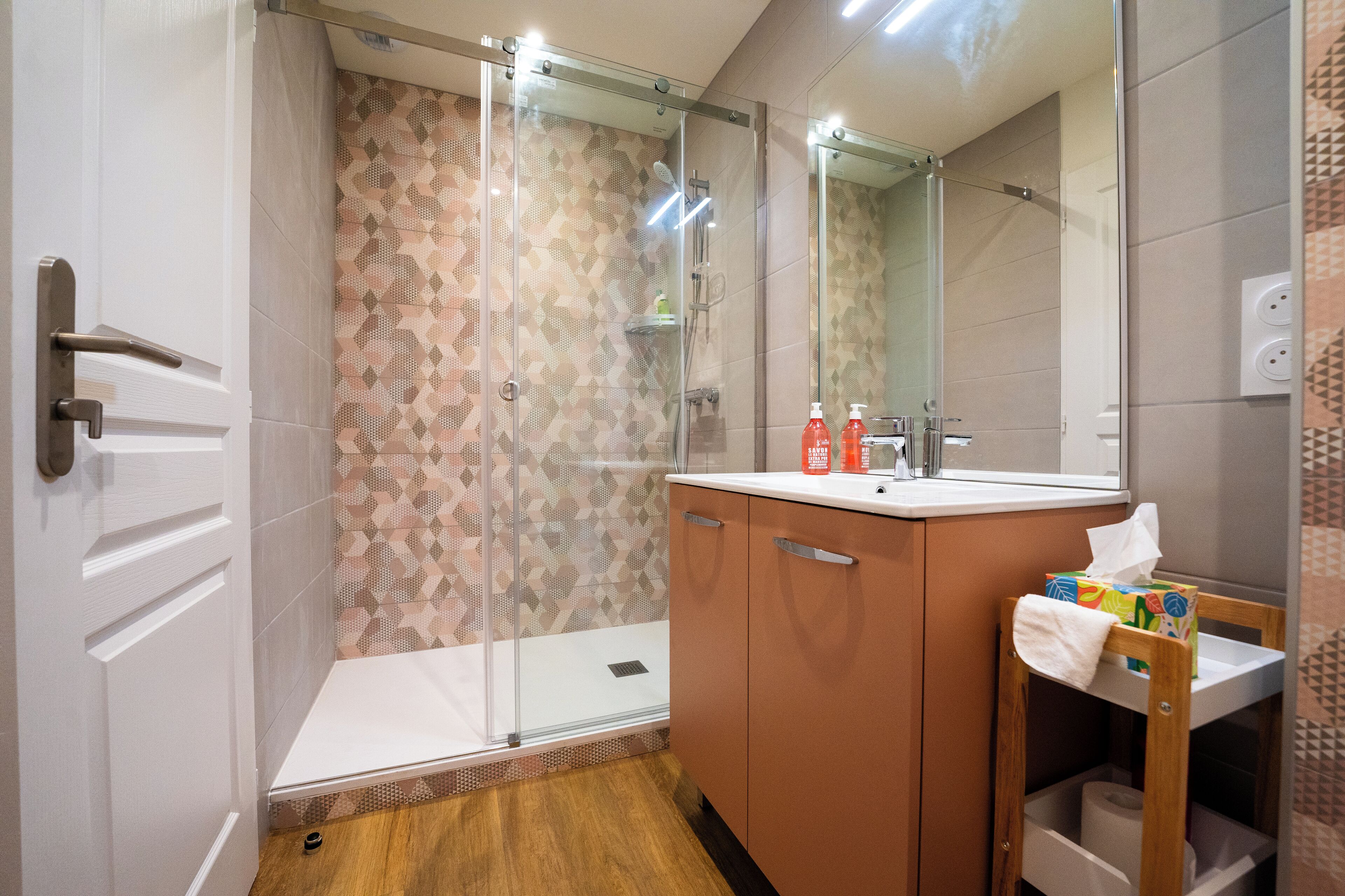 A modern bathroom with a shower, a sink, and a mirror.