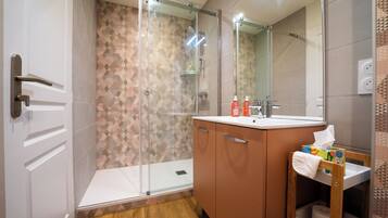Un baño moderno con ducha, lavamanos y espejo.