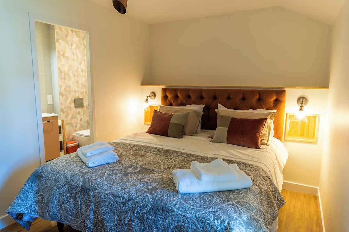 A neatly made bed with a patterned bedspread, two bedside lamps, and a headboard.