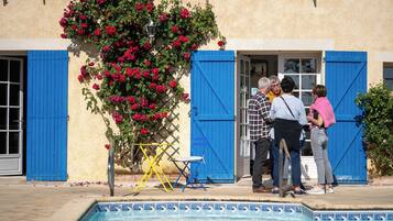 Zona de piscina con una puerta azul, una silla y una mesa.