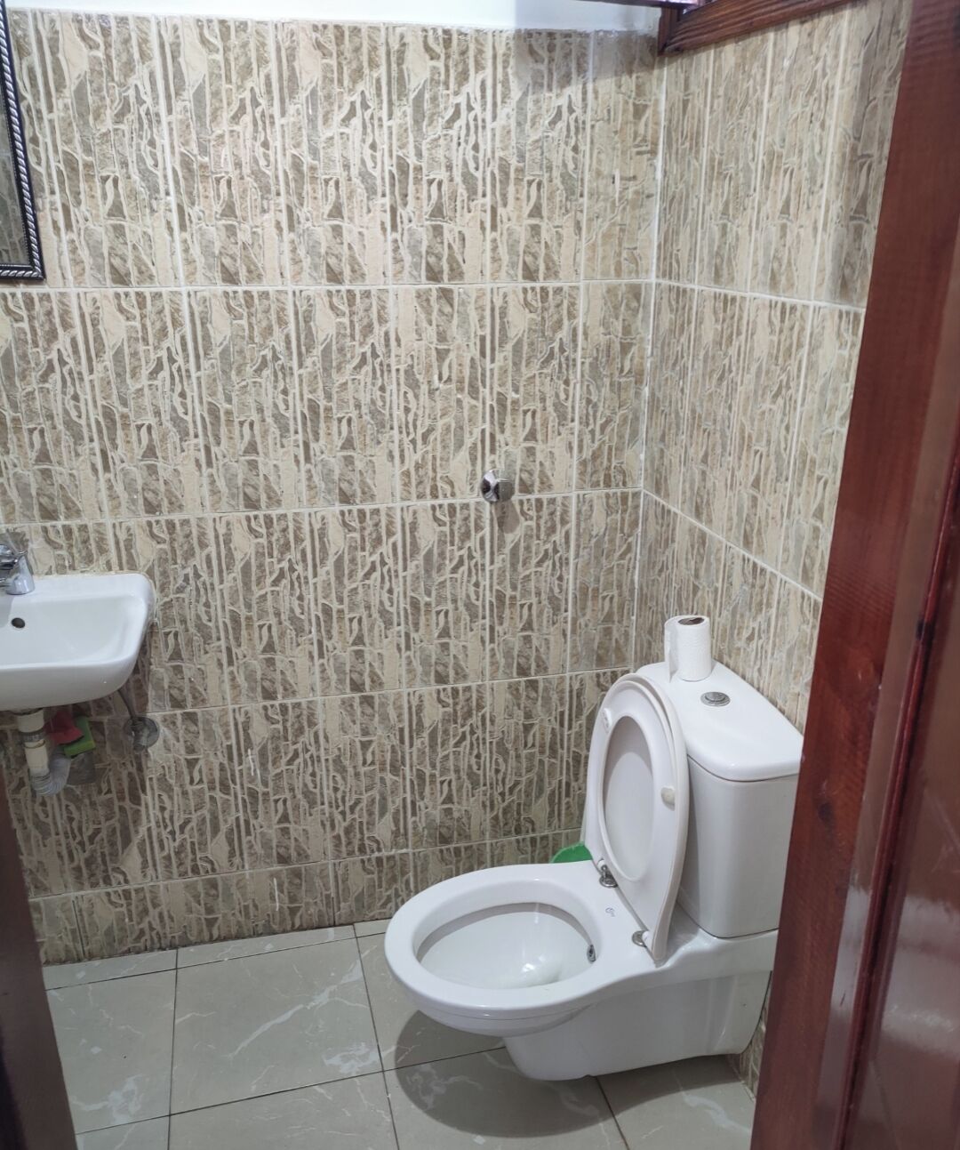 Ein kleines Badezimmer mit Toilette, Waschbecken und Fliesen.